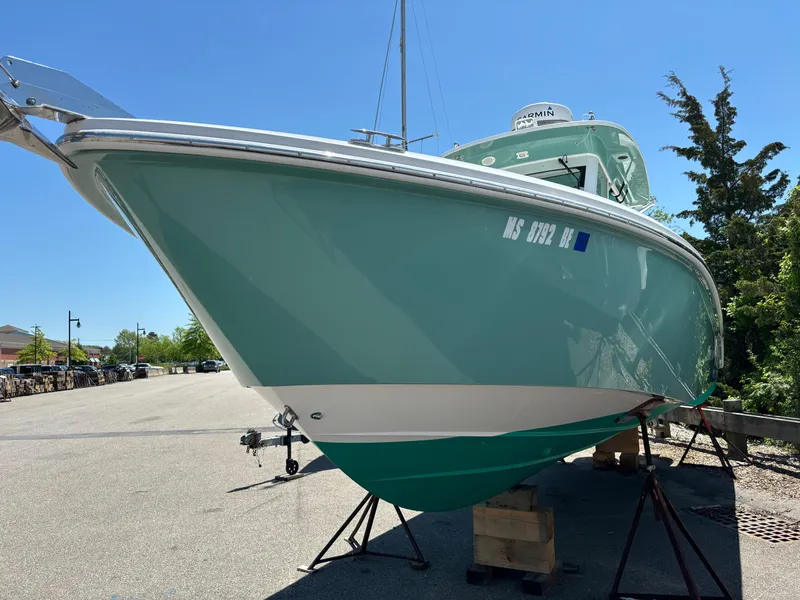 Slide: The Image of 2014 Everglades 295 boat on stands, light blue hull, sunny day. - 2
