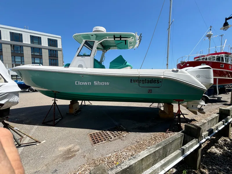Slide: The Image of 2014 Everglades 295 boat on stands, turquoise hull, docked near buildings. - 3