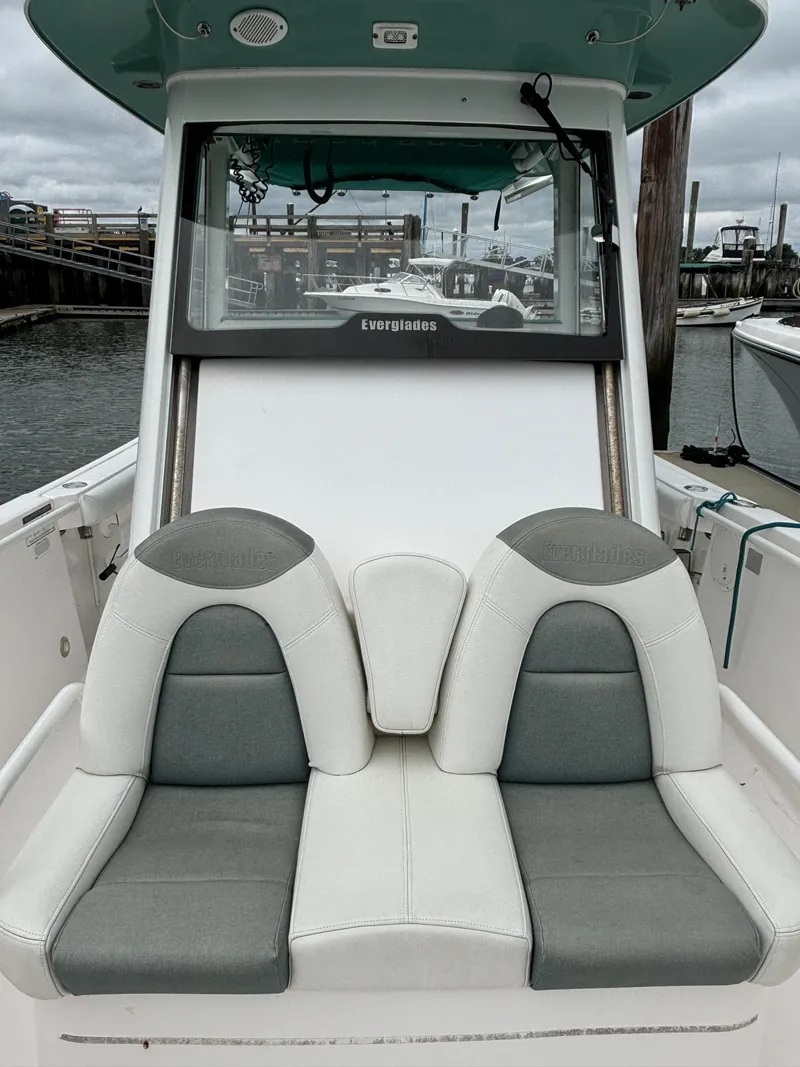 Slide: The Image of 2014 Everglades 295 boat with dual gray and white seats, docked at a marina. - 8