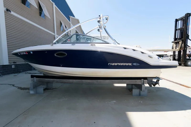 Slide: The Image of 2013 Chaparral 224 Sunesta boat on display, blue and white exterior, docked outdoors. - 1