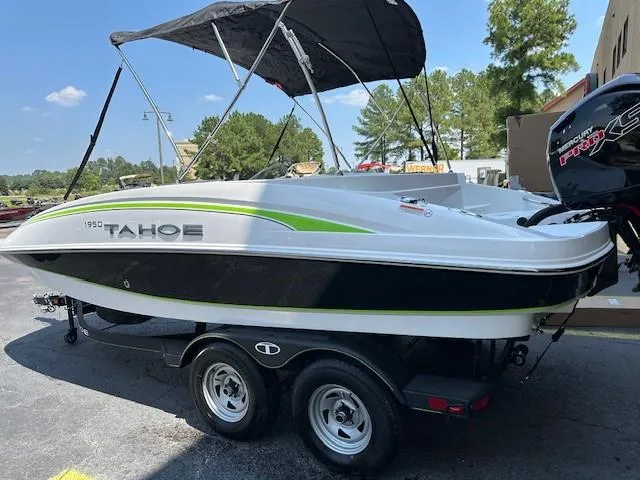 Slide: The Image of 2024 Tahoe 1950 boat on trailer with canopy, parked outdoors. - 2