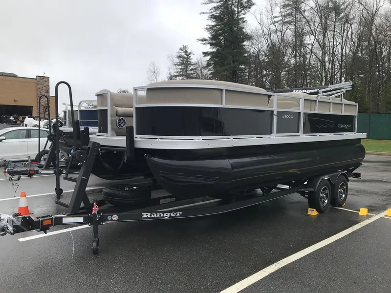 Slide: The Image of 2024 Ranger Reata 200C pontoon boat on trailer in parking lot. - 2