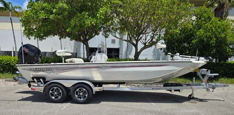 Slide: The Image of 2024 Ranger RB200 boat on trailer, parked outdoors with trees in the background. - 2