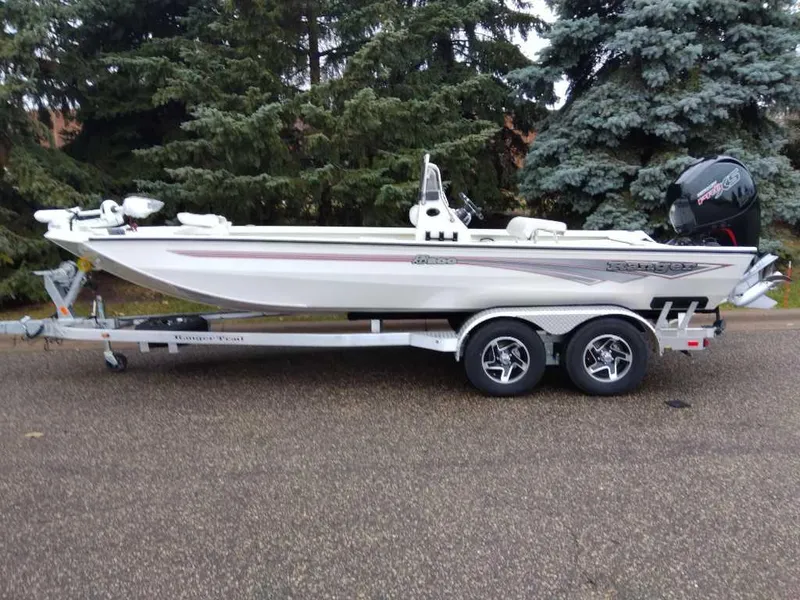 Slide: The Image of 2024 Ranger RB200 boat on trailer, parked on road with trees in background. - 6