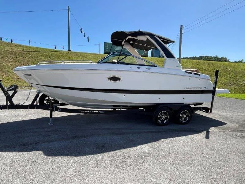 Slide: The Image of 2024 Chaparral 267 SSX boat on trailer, parked outdoors under clear sky. - 12