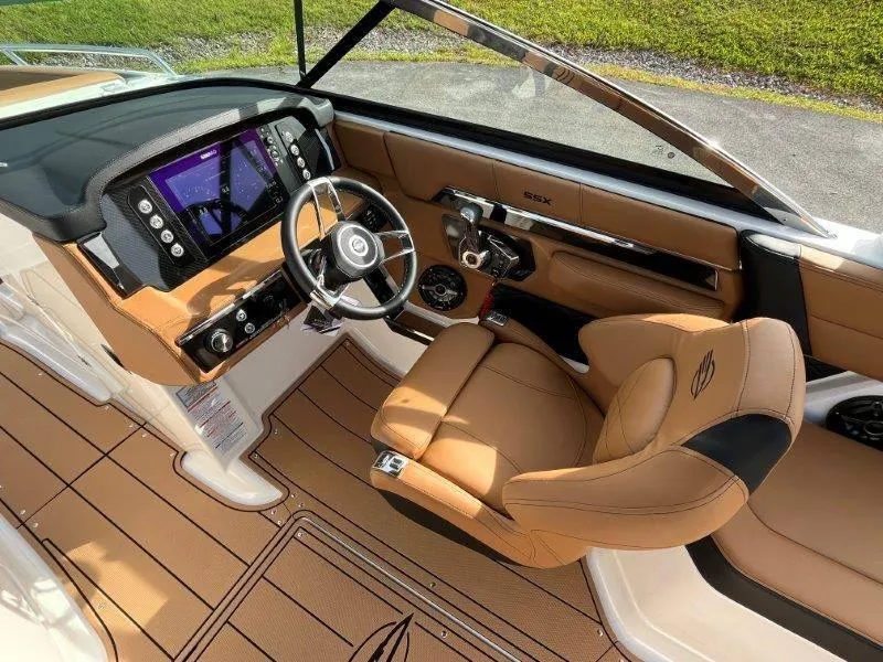 Slide: The Image of 2024 Chaparral 267 SSX boat interior with tan leather seating and modern dashboard. - 25