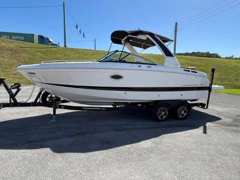 Slide: The Image of 2024 Chaparral 267 SSX boat on trailer, parked outdoors under clear blue sky. - 3