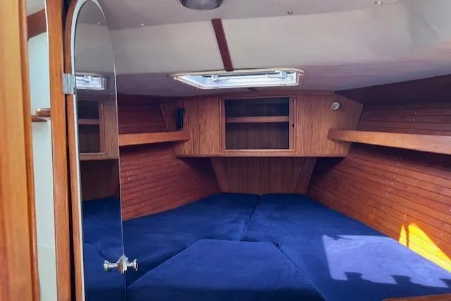Slide: The Image of Cozy cabin interior of a 1994 J Boats J 44, featuring blue cushions and wooden paneling. - 6