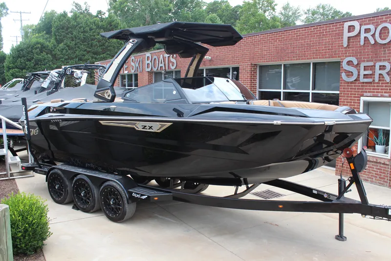 The Image of 2024 Tigé Ultré 23ZX boat on trailer, parked outside a brick building. - 0