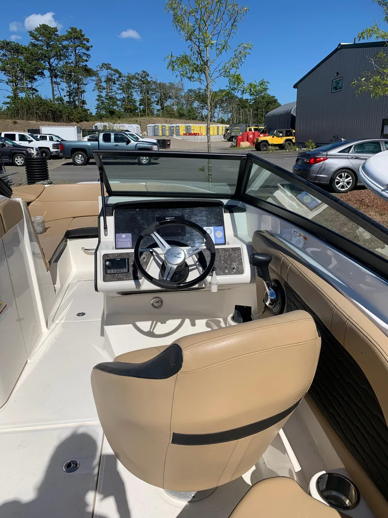 Slide: The Image of 2022 Sea Ray SPX 230 OB boat interior with steering wheel and beige seating. - 5