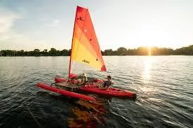 Slide: The Image of 2025 Hobie Tandem Island sailing on a serene lake at sunset. - 2