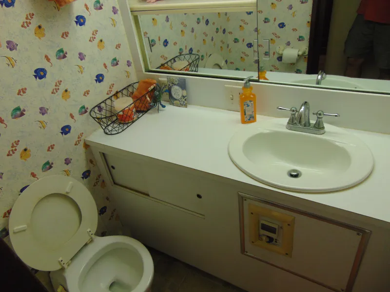 Slide: The Image of 1972 Hatteras Yachtfish bathroom with sink, toilet, fan, and decorative wallpaper. - 23