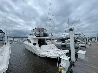 Slide: The Image of 2007 Sea Ray 52 Sedan Bridge yacht docked at marina under cloudy sky. - 2