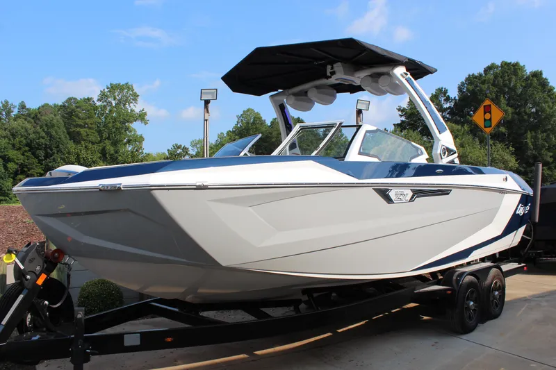 Slide: The Image of 2025 Tigé Ultré 25ZX boat on trailer, sleek design, parked outdoors. - 2