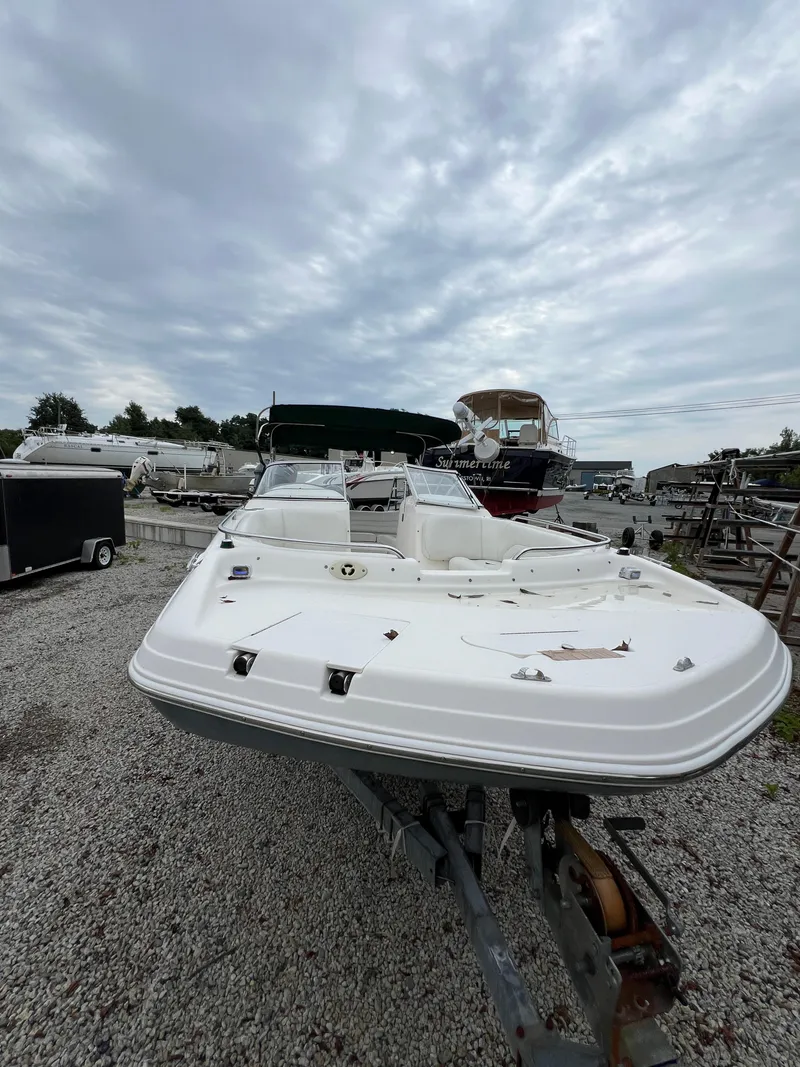 Slide: The Image of 2006 Hurricane SunDeck 237 DC OB boat on trailer, parked in a gravel lot. - 14