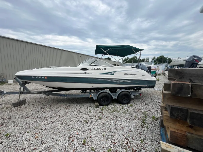 Slide: The Image of 2006 Hurricane SunDeck 237 DC OB boat on trailer, parked outdoors under cloudy sky. - 2