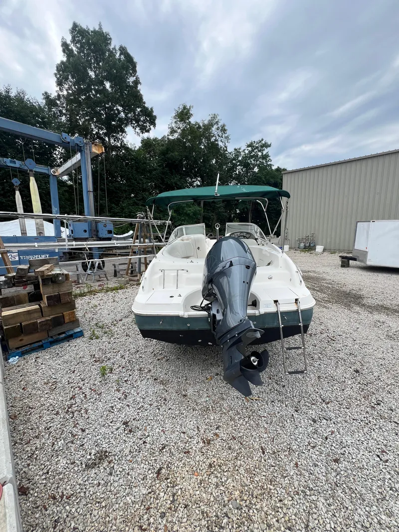 Slide: The Image of 2006 Hurricane SunDeck 237 DC OB boat with outboard motor in a gravel yard. - 5
