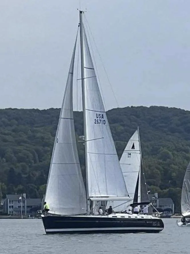 Slide: The Image of 2007 Beneteau Oceanis Clipper 523 sailing on a calm lake with forested hills in the background. - 2
