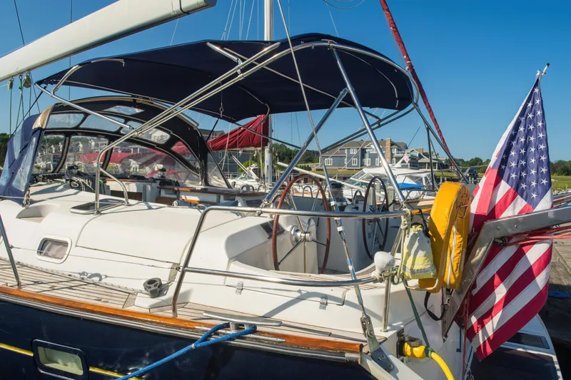 Slide: The Image of 2007 Beneteau Oceanis Clipper 523 sailboat docked, featuring American flag and blue canopy. - 43