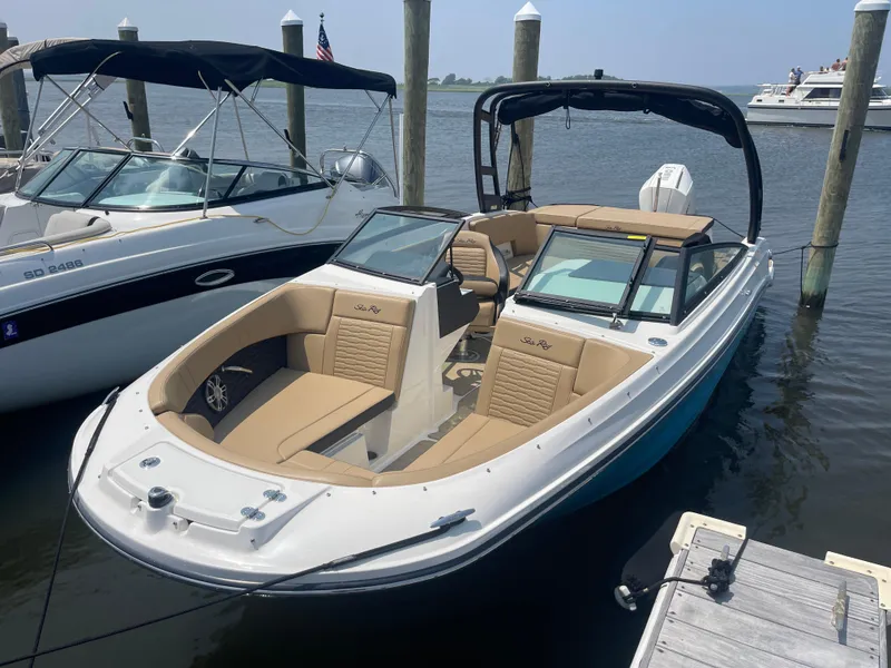 Slide: The Image of 2023 Sea Ray SPX 230 Outboard boat docked, featuring sleek design and spacious seating. - 2