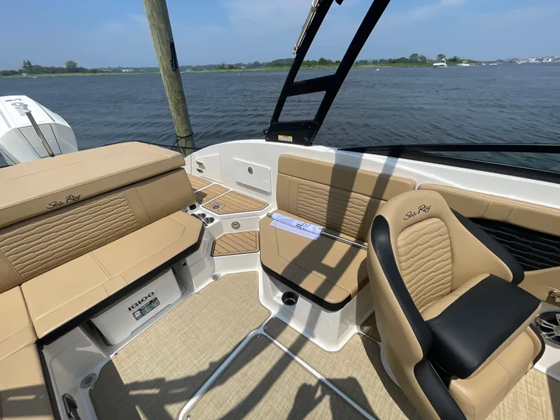 Slide: The Image of 2023 Sea Ray SPX 230 Outboard interior with tan seating, on a sunny day by the water. - 21