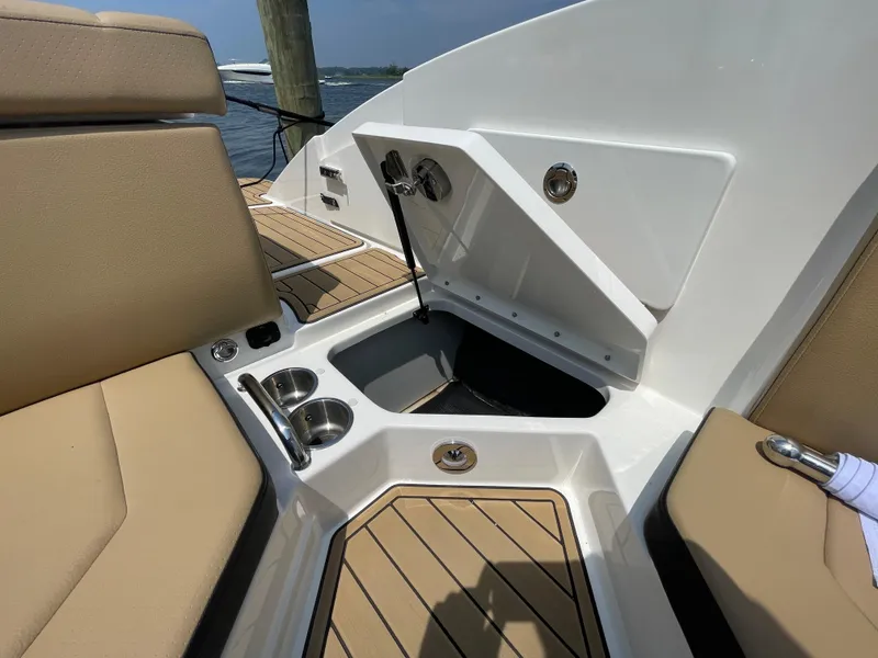 Slide: The Image of 2023 Sea Ray SPX 230 Outboard interior with storage compartment and cup holders. - 27