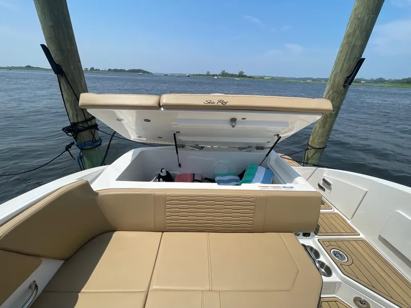 Slide: The Image of 2023 Sea Ray SPX 230 Outboard boat with open storage compartment, docked by the water. - 29