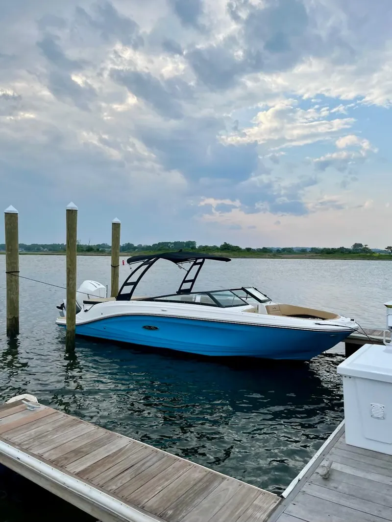 Slide: The Image of 2023 Sea Ray SPX 230 OB boat docked on a serene lake under a cloudy sky. - 37