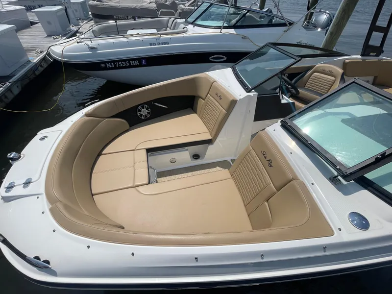 Slide: The Image of 2023 Sea Ray SPX 230 Outboard boat with tan seating, docked at a marina. - 4