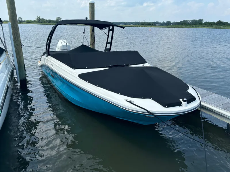 Slide: The Image of 2023 Sea Ray SPX 230 OB boat docked on calm water, covered with black tarp. - 40