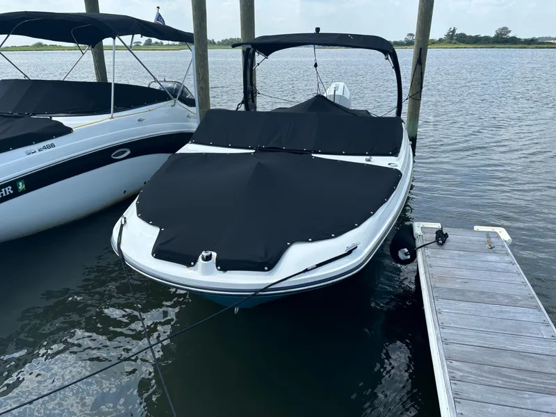 Slide: The Image of 2023 Sea Ray SPX 230 OB boat docked with black cover on water. - 41