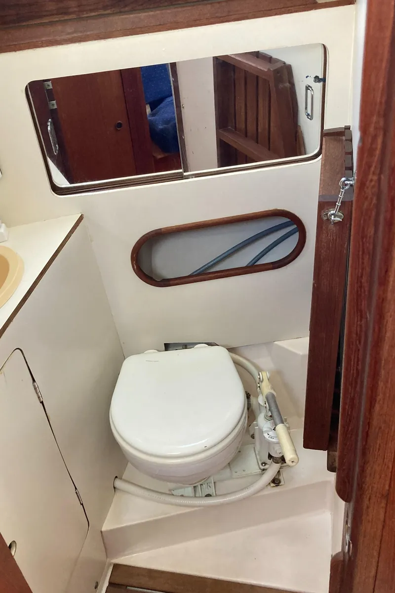 Slide: The Image of 1984 Hunter 31 sailboat bathroom with toilet, mirror, and wooden accents. - 15