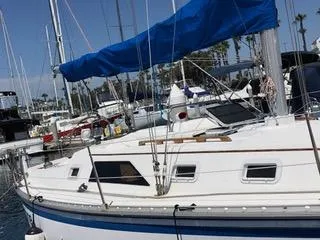 Slide: The Image of 1984 Hunter 31 sailboat with blue sail cover docked in marina. - 19