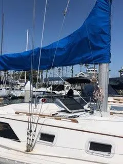 Slide: The Image of 1984 Hunter 31 sailboat with blue sail cover docked in marina. - 20