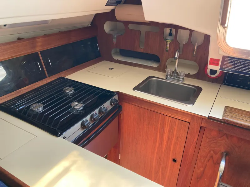 Slide: The Image of 1984 Hunter 31 yacht kitchen with stove, sink, and wooden cabinetry. - 29