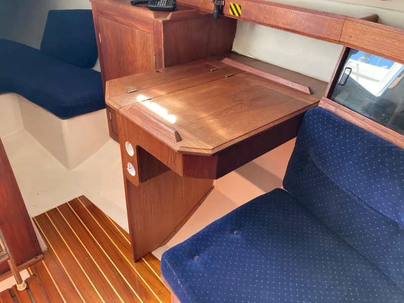 Slide: The Image of 1984 Hunter 31 sailboat interior with wooden desk and blue cushioned seating. - 31