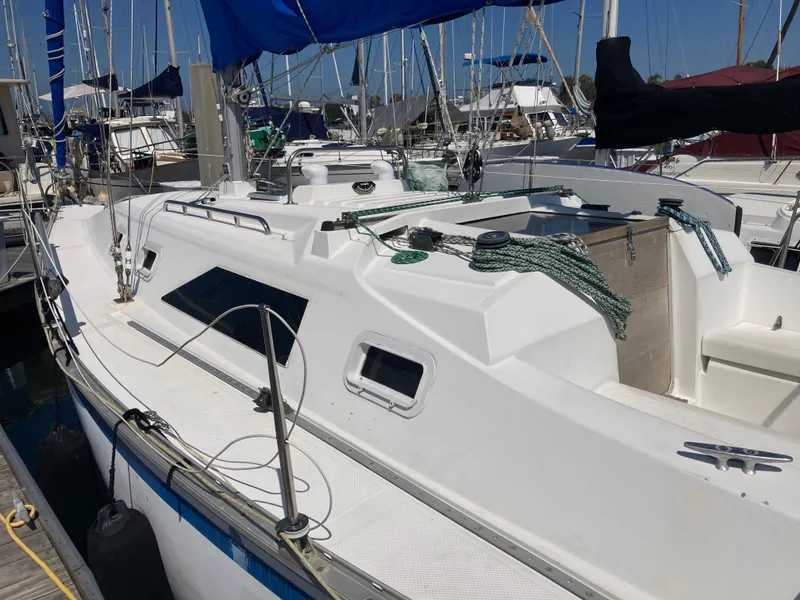 Slide: The Image of 1984 Hunter 31 sailboat docked at marina, featuring white deck and blue sail. - 34