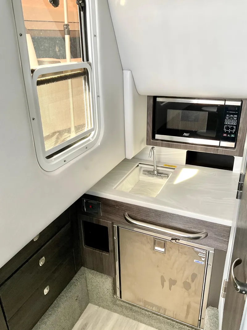 Slide: The Image of 2022 Formula 350 Crossover Bowrider I/O interior kitchen with sink, microwave, and fridge. - 15