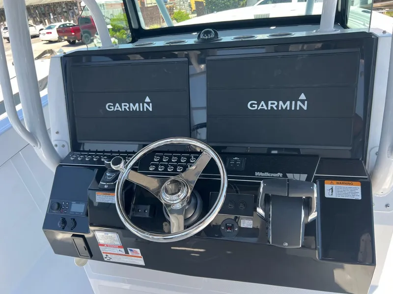 Slide: The Image of 2025 Wellcraft 352 Fisherman boat dashboard with Garmin displays and steering wheel. - 27