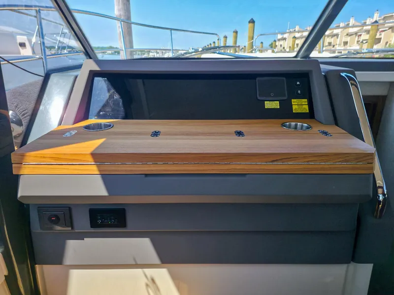 Slide: The Image of 2026 Marex 440 yacht dashboard with wooden panel and cup holders, docked at marina. - 54