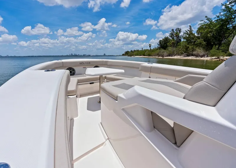 Slide: The Image of 2025 Solace 32 CS boat interior with seating, table, and scenic water view. - 11