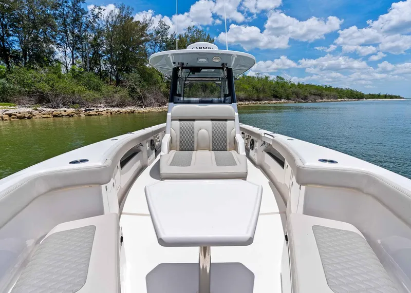 Slide: The Image of 2025 Solace 32 CS boat interior with seating and table, docked by a scenic shoreline. - 15