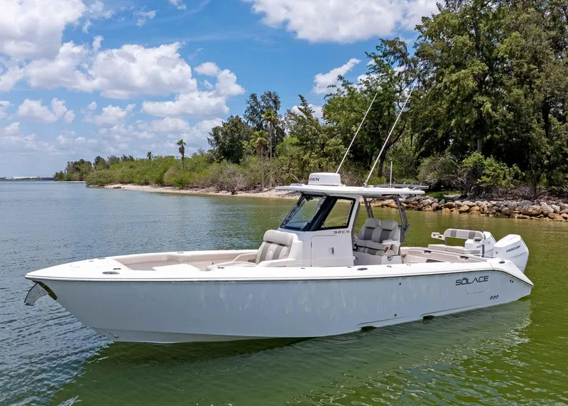 Slide: The Image of 2025 Solace 32 CS boat on calm water, surrounded by lush greenery and blue sky. - 2