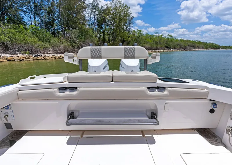 Slide: The Image of 2025 Solace 32 CS boat interior with seating, near lush shoreline and blue sky. - 27