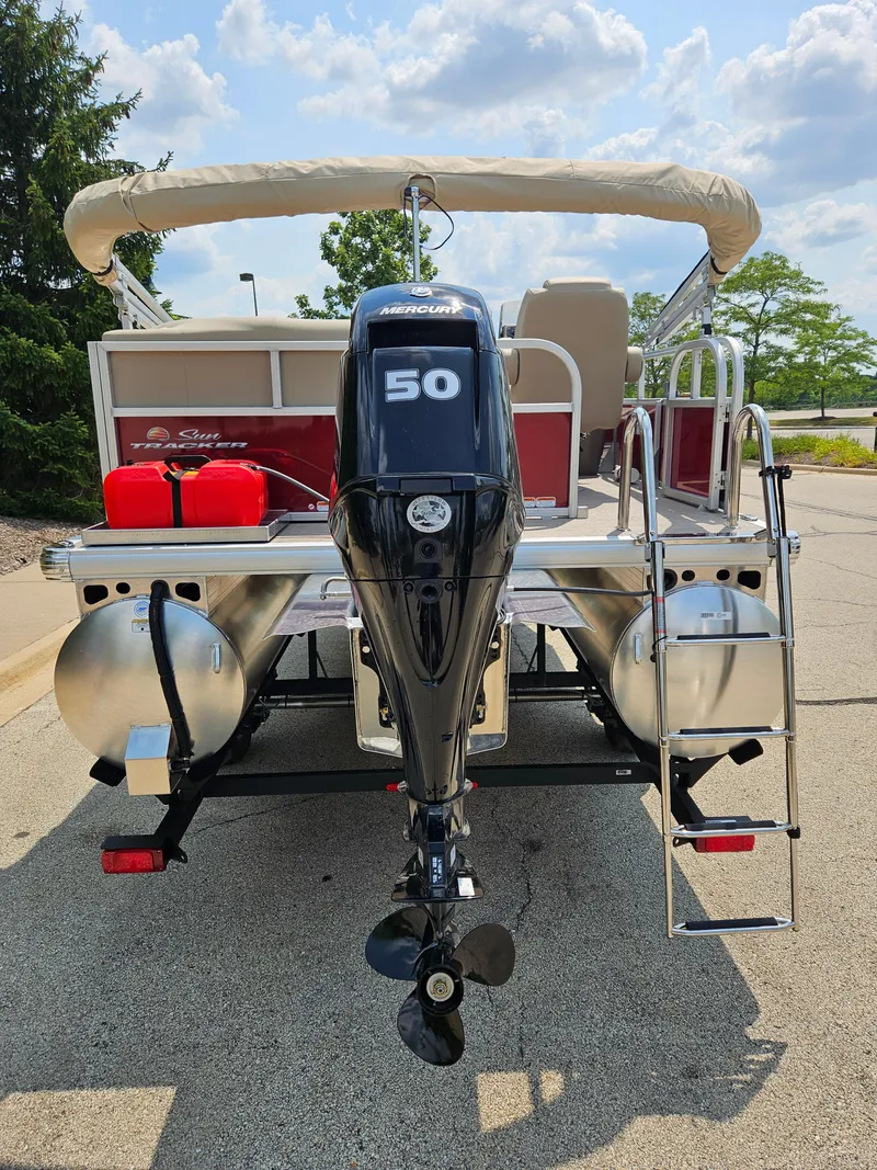 Slide: The Image of 2025 Bass Tracker BB16XLS boat with outboard motor and ladder, parked outdoors. - 4