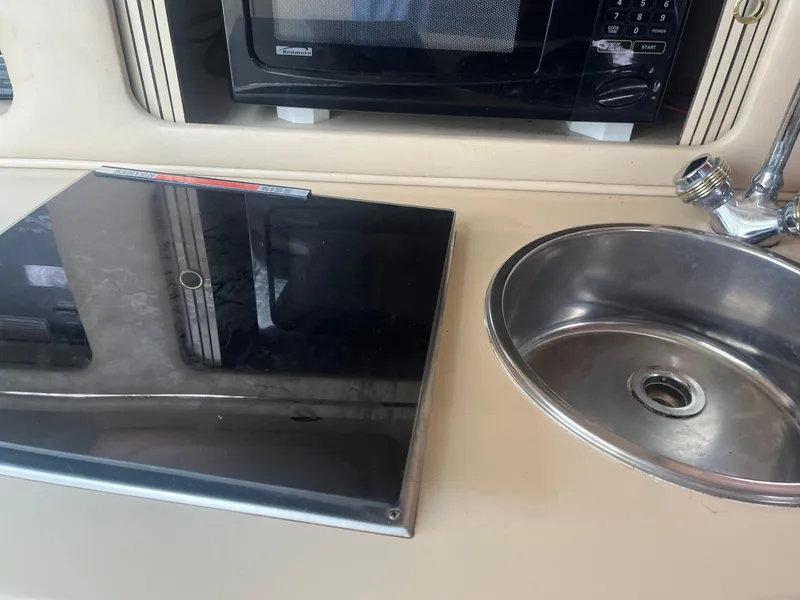 Slide: The Image of 1995 Sea Ray 250 Sundancer kitchen area with stove, sink, and microwave. - 18