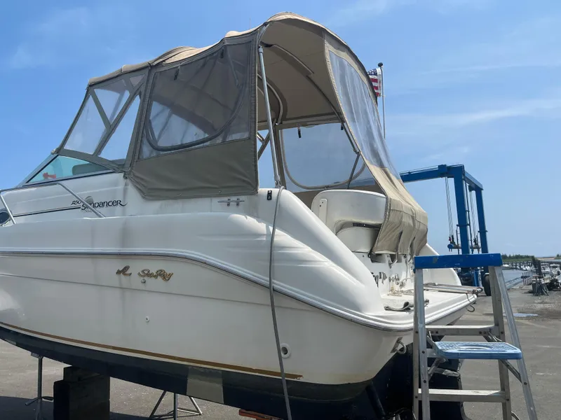 Slide: The Image of 1995 Sea Ray 250 Sundancer boat with canopy, docked on land under clear sky. - 25