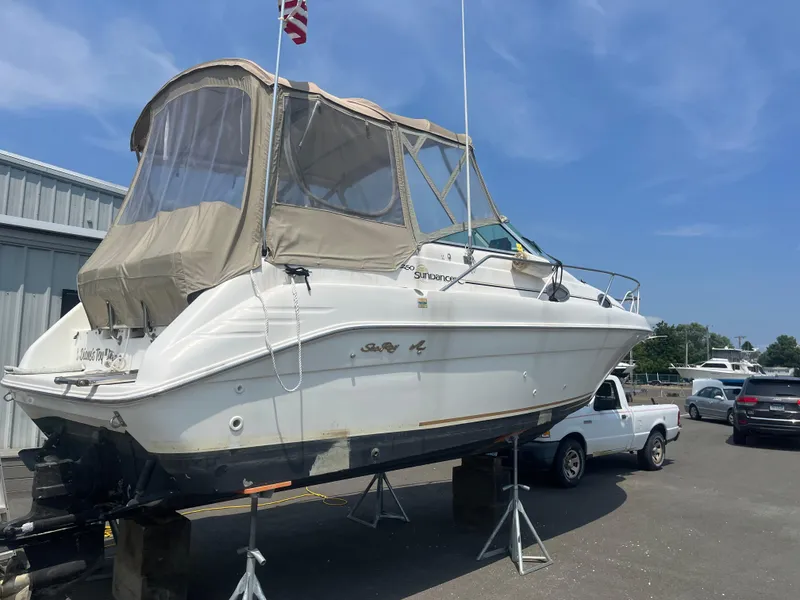Slide: The Image of 1995 Sea Ray 250 Sundancer boat on stands, outdoor storage, clear sky. - 28