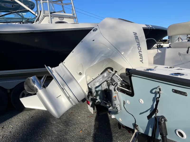 Slide: The Image of 2025 Boston Whaler 210 Montauk with Mercury outboard engine, parked on gravel. - 2