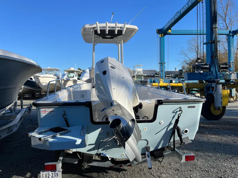 Slide: The Image of 2025 Boston Whaler 210 Montauk boat on trailer, rear view, in a marina setting. - 21